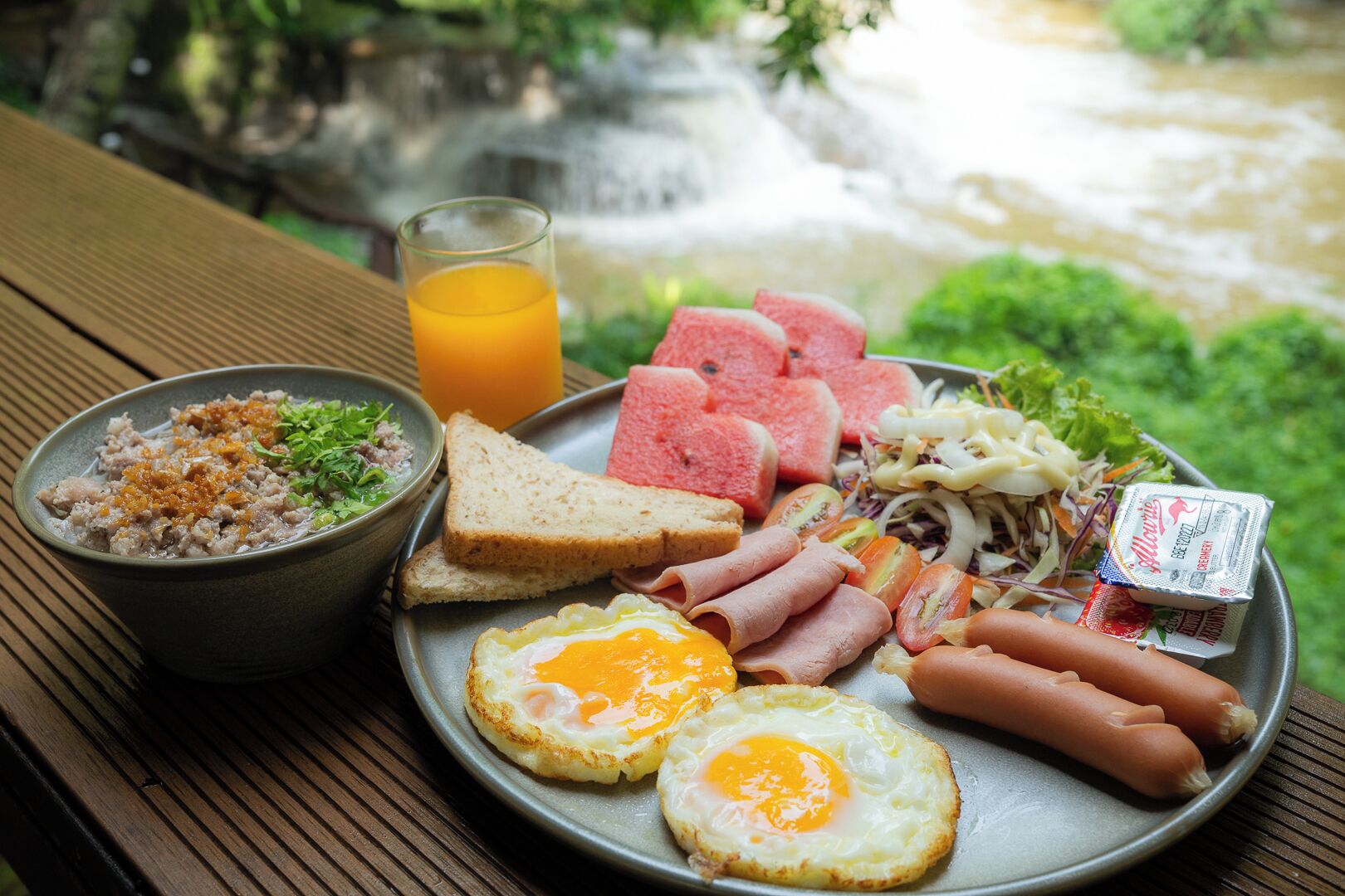 A breakfast plate with eggs, sausages, ham, toast, and a bowl of salad.