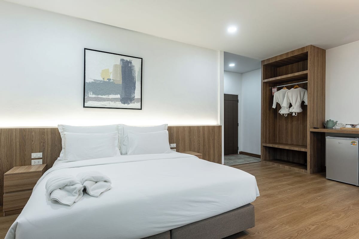 A hotel room with a bed, a nightstand, a wardrobe, and a small kitchenette.