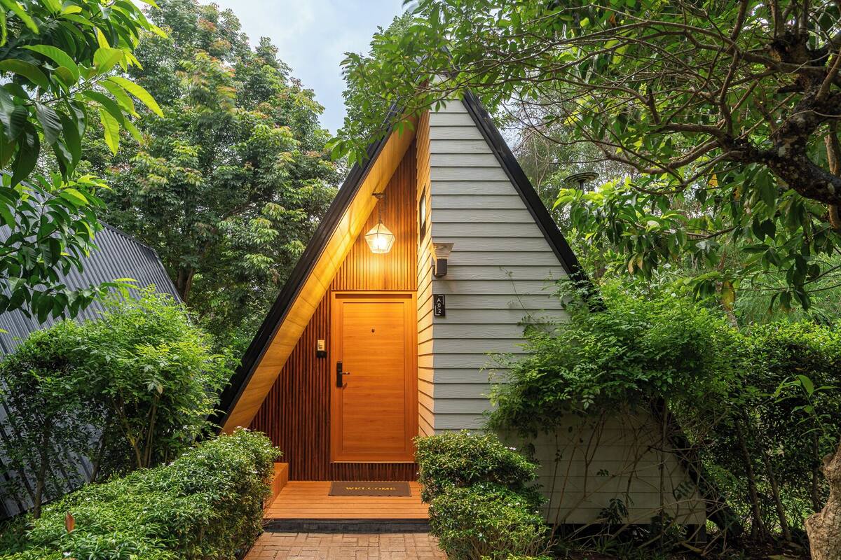 Una casa de madera con techo inclinado, puerta principal y felpudo.