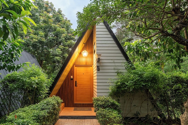 Una casa de madera con techo inclinado, puerta principal y felpudo.