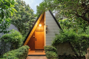 A wooden house with a sloped roof, a front door, and a welcome mat.