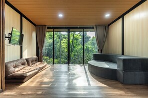 Ein modernes Wohnzimmer mit einer Couch, einer gebogenen Sitzecke und einem an der Wand befestigten Fernseher.