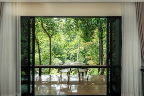 Un comedor con una mesa y sillas, ventanas amplias y vista a un bosque.