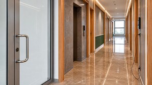 En modern hall med ett marmorgolv, träpanel och en glasdörr med ett handtag.