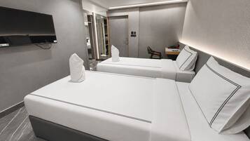 A modern hotel room with two beds, a flat-screen TV, a desk, and a mirror.