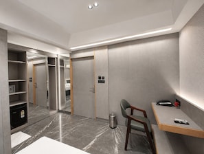 Ein modernes Hotelzimmer mit Schreibtisch, Stuhl und Kleiderschrank.