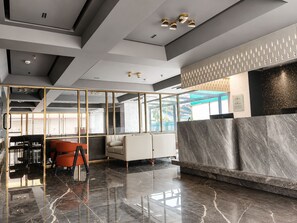 A modern reception area with a marble reception desk, seating, and a glass partition. - Hotel Aston Residency (Kolkata)
