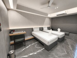 A modern hotel room with a desk, two beds, a ceiling fan, and a marble floor. - Hotel Aston Residency (Kolkata)