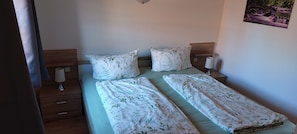 Ein Doppelbett mit floralem Bettzeug, zwei Nachttische mit Lampen und ein Wandbild.