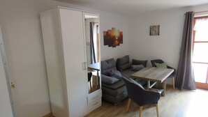 Ein modernes Wohnzimmer mit einer Couch, einem Esstisch und einem Kleiderschrank.