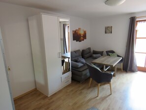 Ein modernes Wohnzimmer mit einer Couch, einem Esstisch und einem Kleiderschrank.