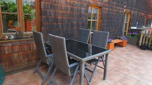 Eine Terrasse im Freien mit Tisch und Stühlen, einer Holzverkleidung und einem Fenster.