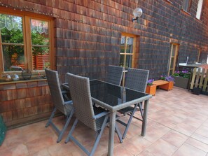 Eine Terrasse im Freien mit Tisch und Stühlen, einer Holzverkleidung und einem Fenster.