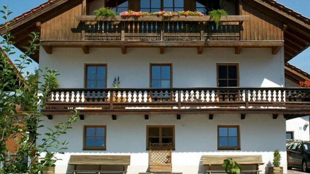 Ein zweistöckiges Gebäude mit Balkon, Holzbalken und heller Fassade.