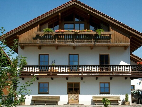 Ein zweistöckiges Gebäude mit Balkon, Holzbalken und heller Fassade.