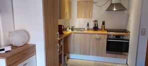 Eine kleine Küche mit Holzschränken, einem eingebauten Ofen und einer Kaffeemaschine.