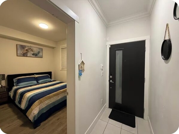 A bedroom with a bed, a nightstand, a painting on the wall, a door, and a small decorative item on the wall. - Private room in surrey (Surrey)