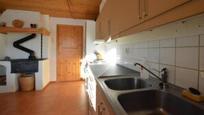 Eine Küche mit Holzschränken, einem Herd, einem Spülbecken und einer gefliesten Spritzschutzwand.
