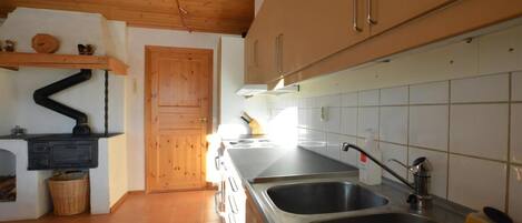 A kitchen with wooden cabinets, a stove, a sink, and a tiled backsplash.