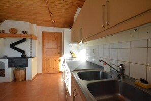 A kitchen with wooden cabinets, a stove, a sink, and a tiled backsplash.