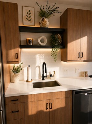 A modern kitchen with wooden cabinets, a white countertop, a black faucet, and a dishwasher. - The Monroe Boutique Near Downtown (Atlanta)