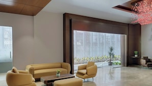 Een moderne lobby met een zithoek, een bijzettafeltje en een potplant.
