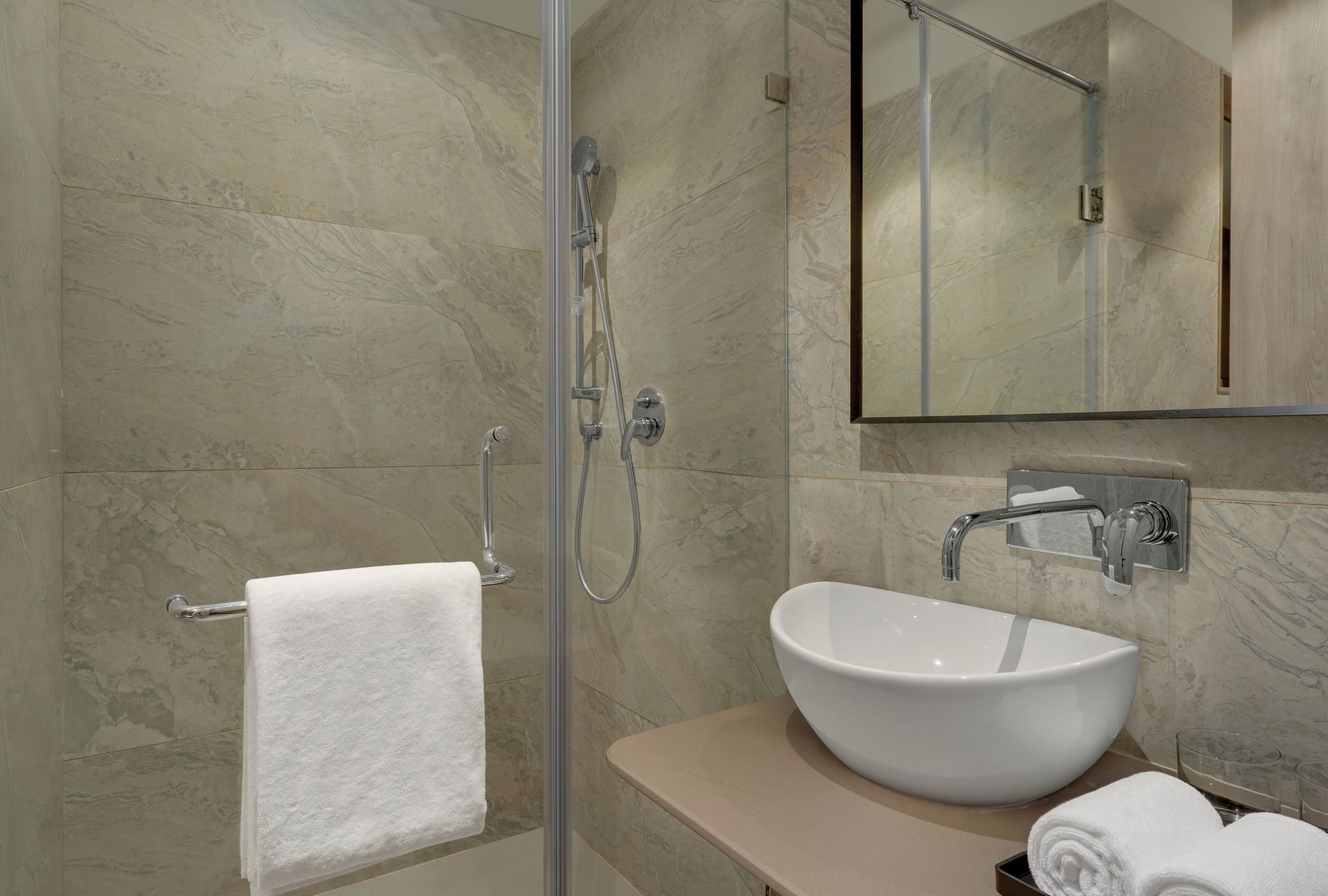 A modern bathroom with a glass-enclosed shower, a white sink, and a large mirror.