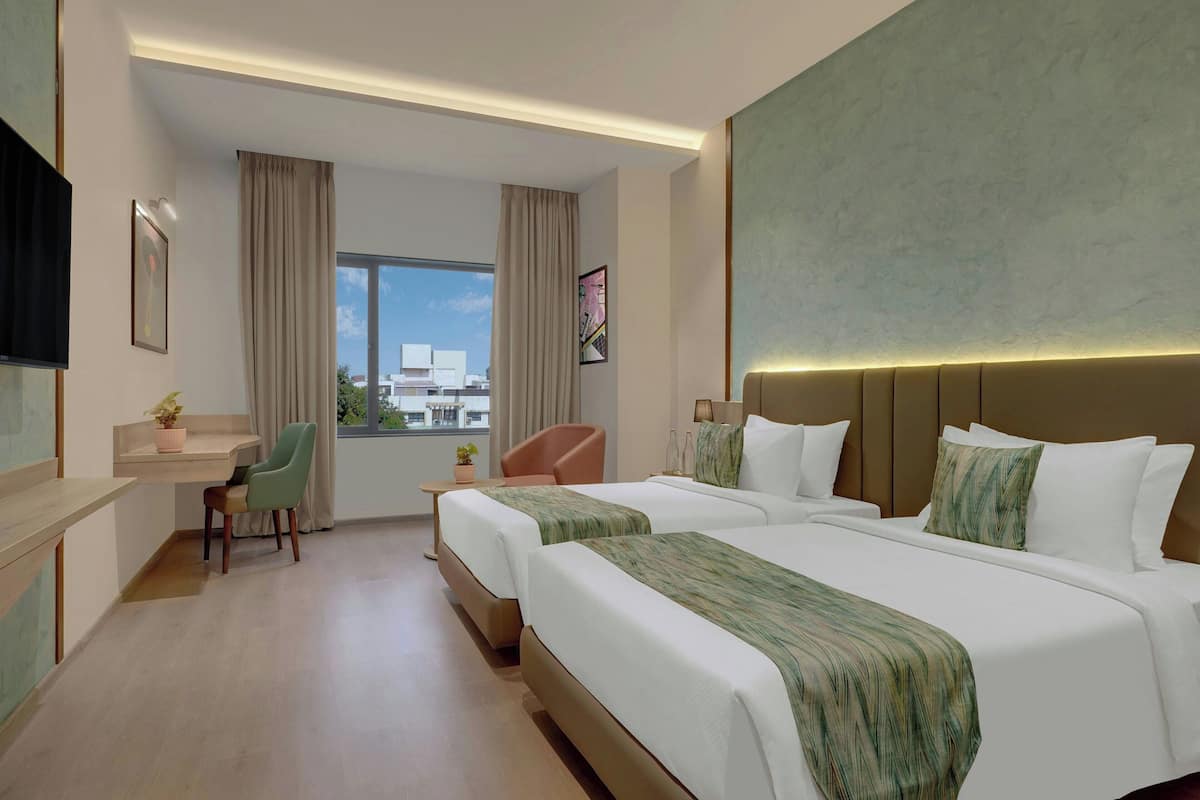 Une chambre d’hôtel avec deux lits, un bureau, une chaise, une fenêtre donnant sur un beau paysage et un téléviseur à écran plat.