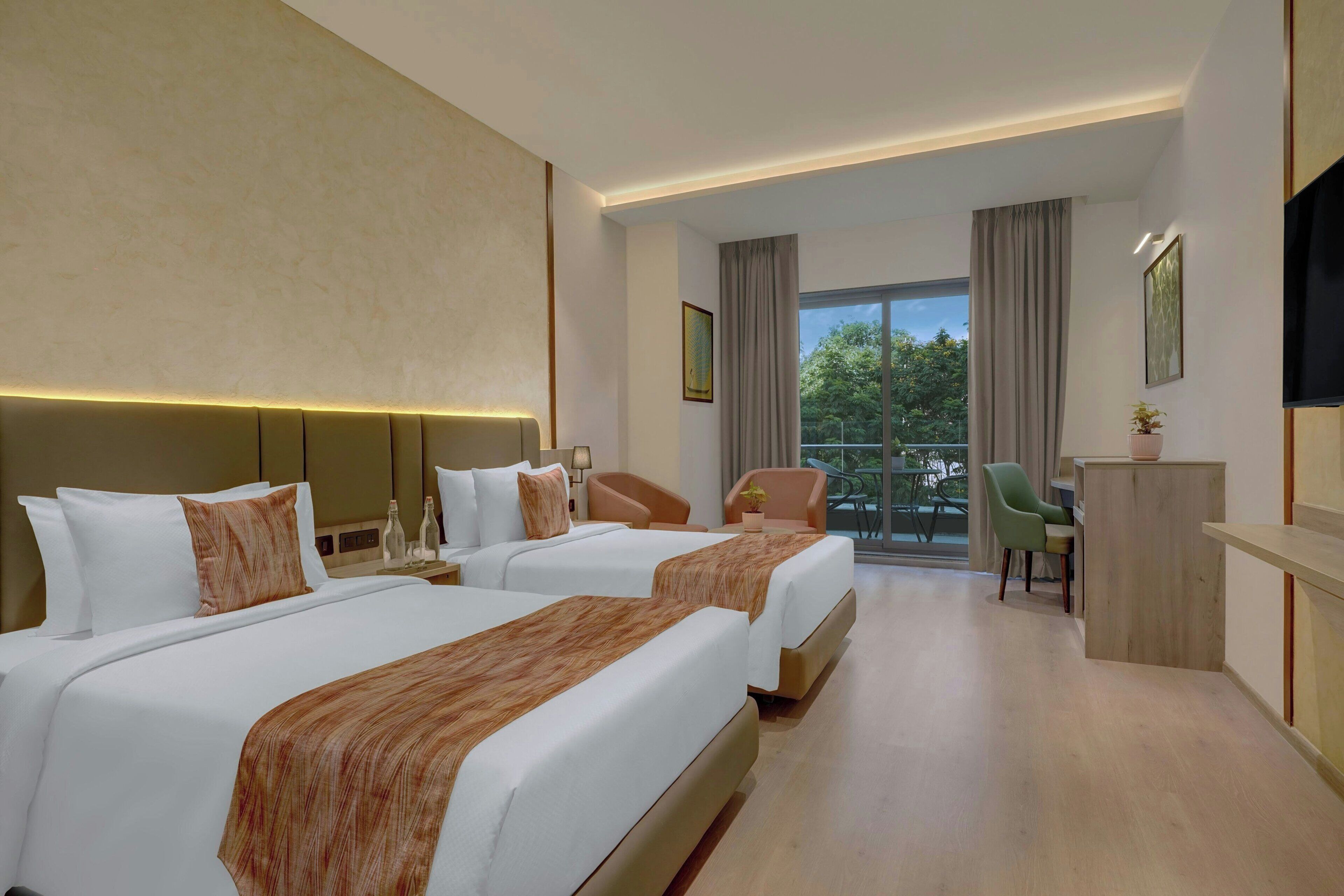 A hotel room with two beds, a desk, a chair, a TV, and a balcony with a view.