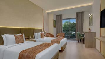A hotel room with two beds, a desk, a chair, a TV, and a balcony with a view.