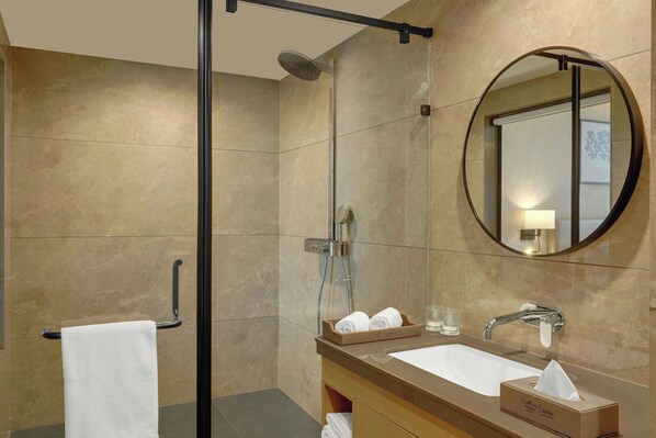 Une salle de bain moderne avec une douche à parois de verre, un lavabo avec un miroir et un porte-serviettes.