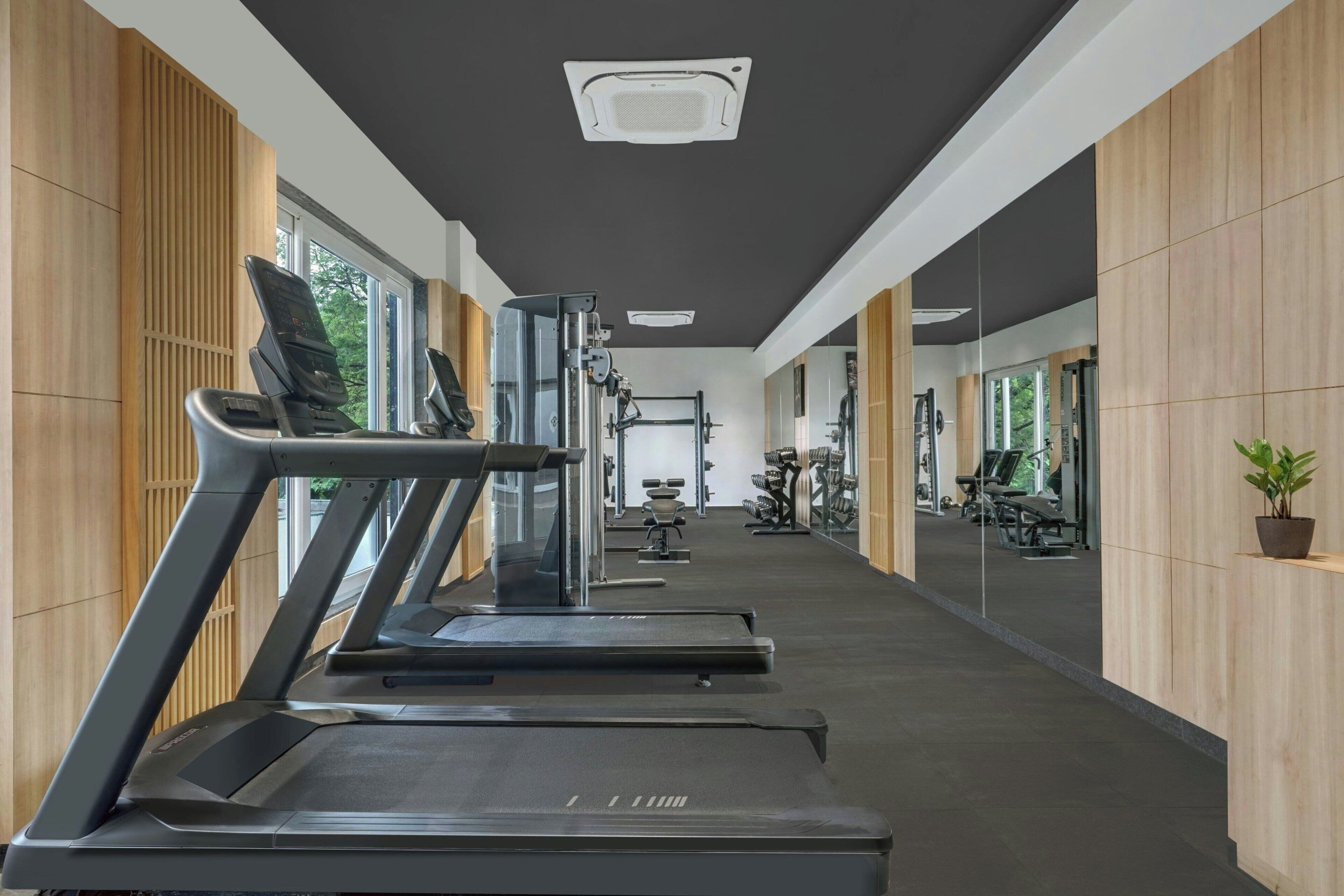 A gym with treadmills, weight machines, and a large mirror.