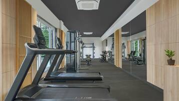A gym with treadmills, weight machines, and a large mirror.