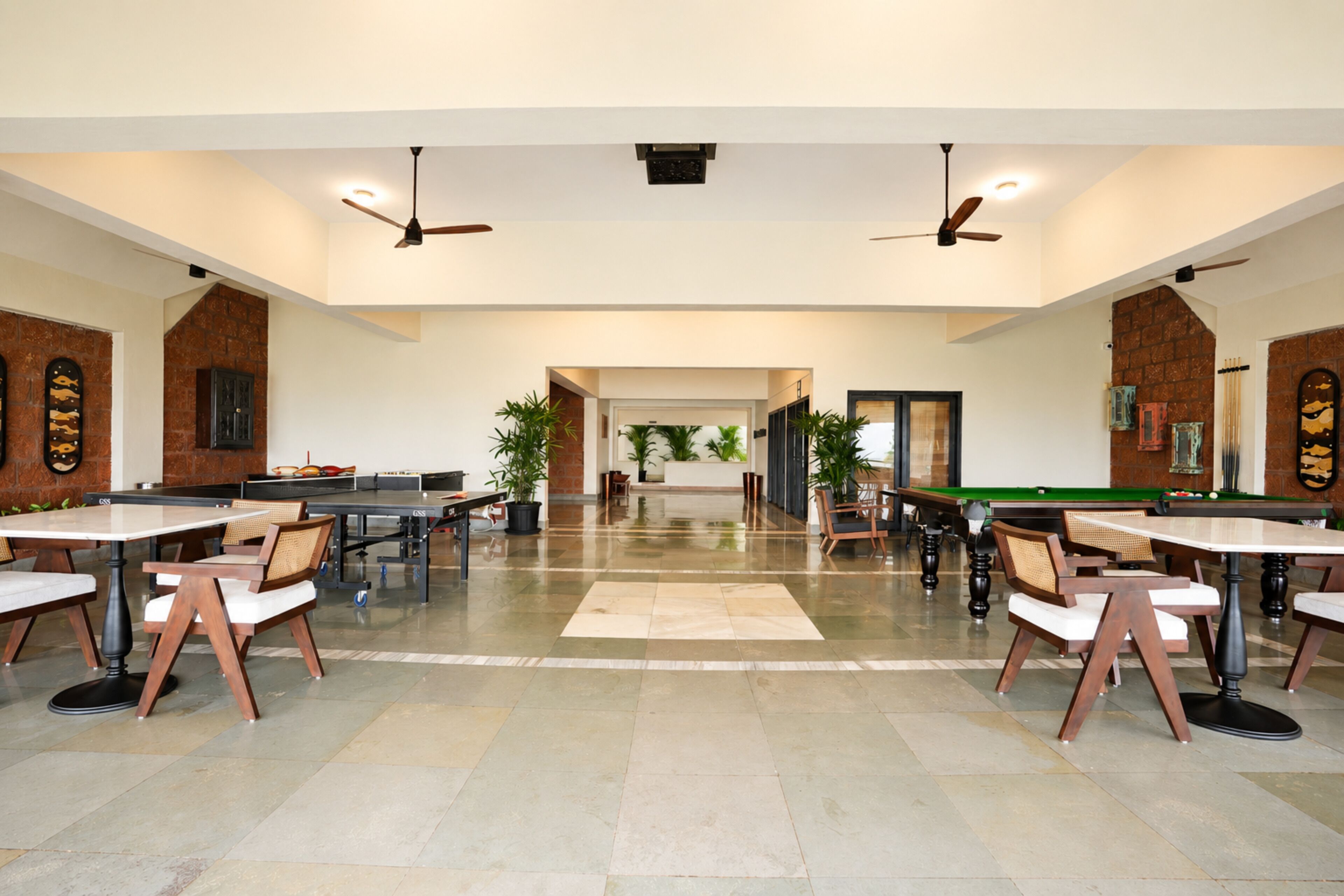 A spacious indoor area with multiple tables and chairs, ceiling fans, and a billiards table.
