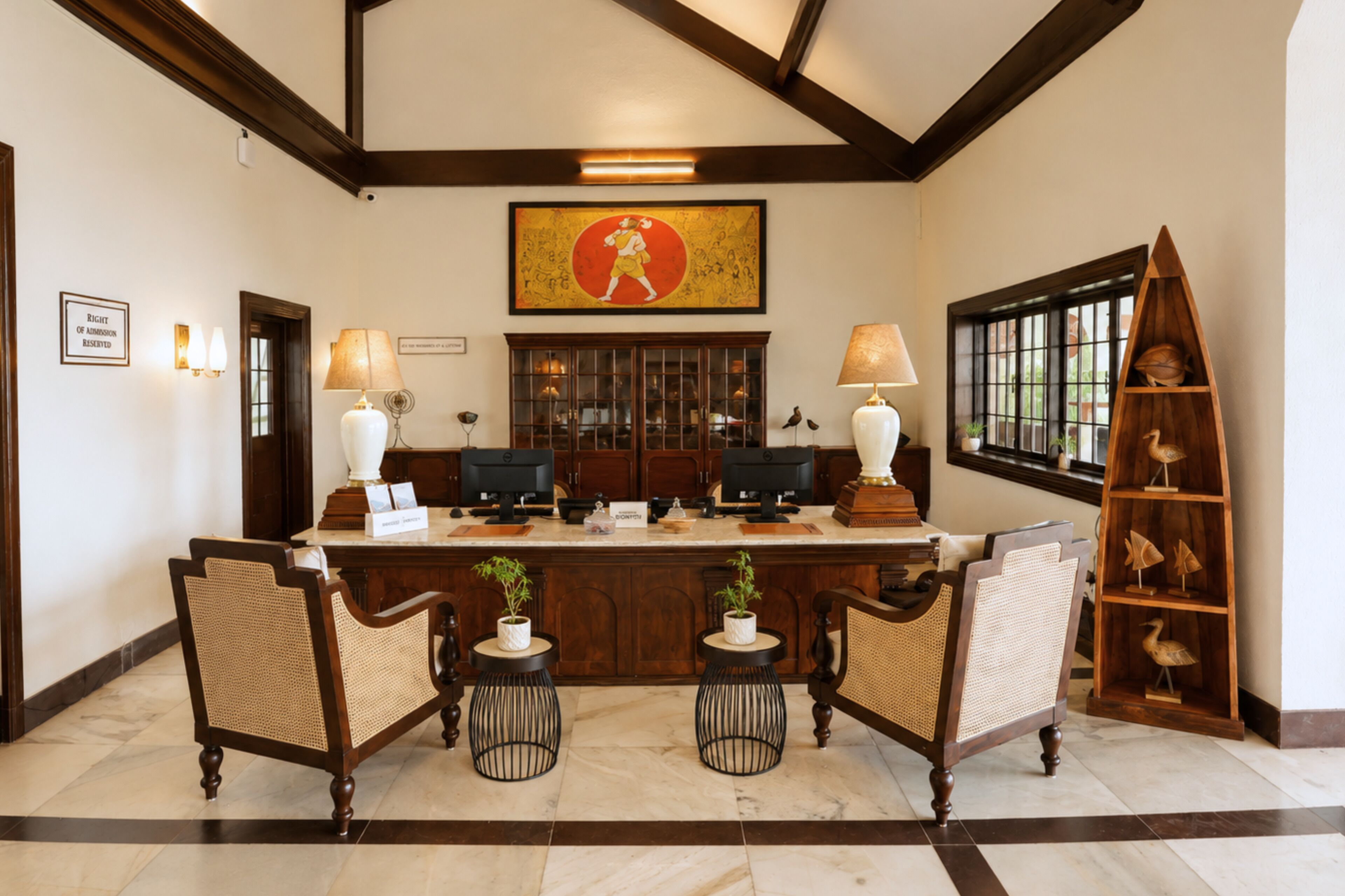 A reception area with a marble floor, wooden reception desk, two computer monitors, two wall-mounted lamps, and a large framed artwork above the desk.