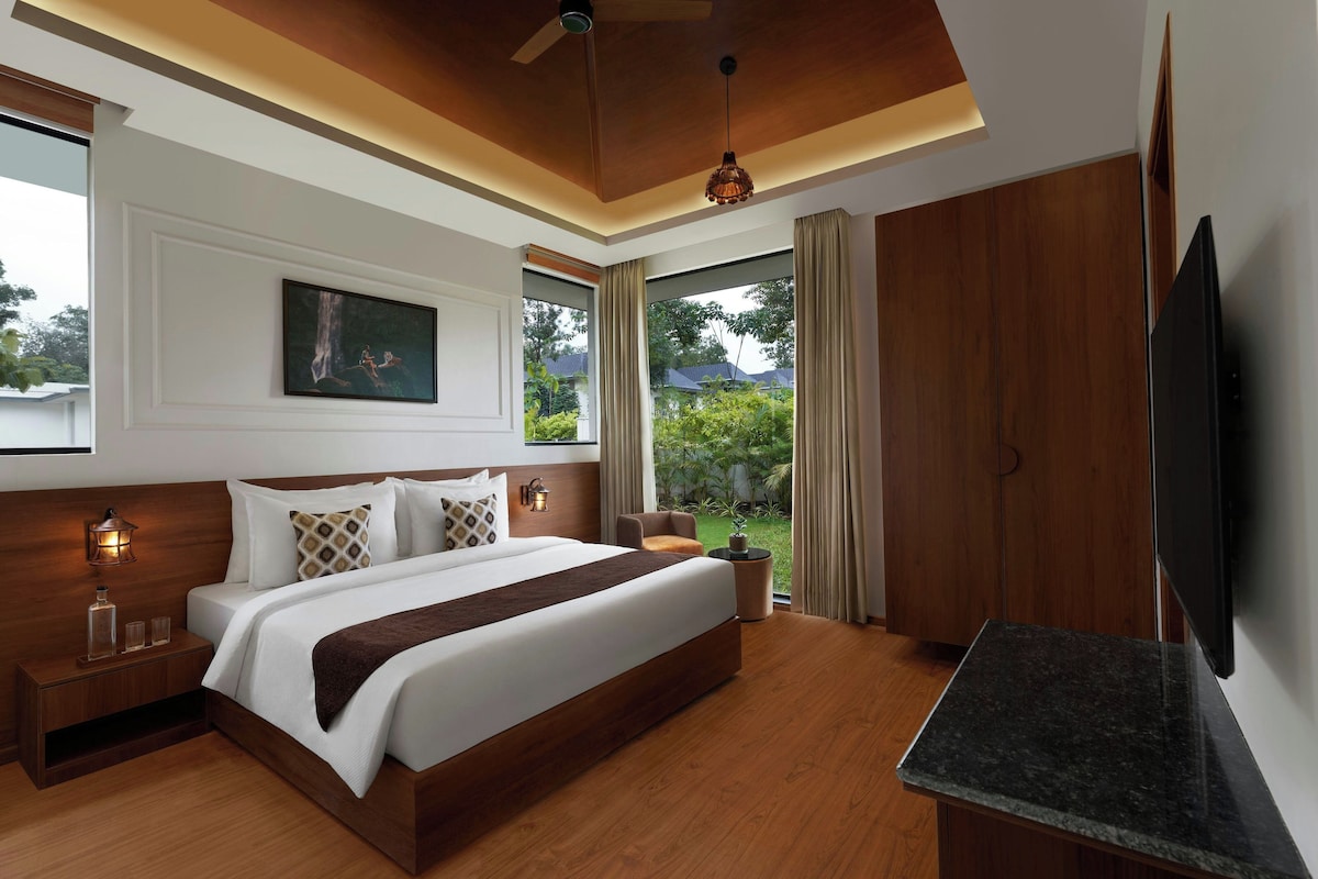 Een moderne hotelkamer met een groot bed, een flatscreen televisie, een plafondventilator en uitzicht op het landschap.