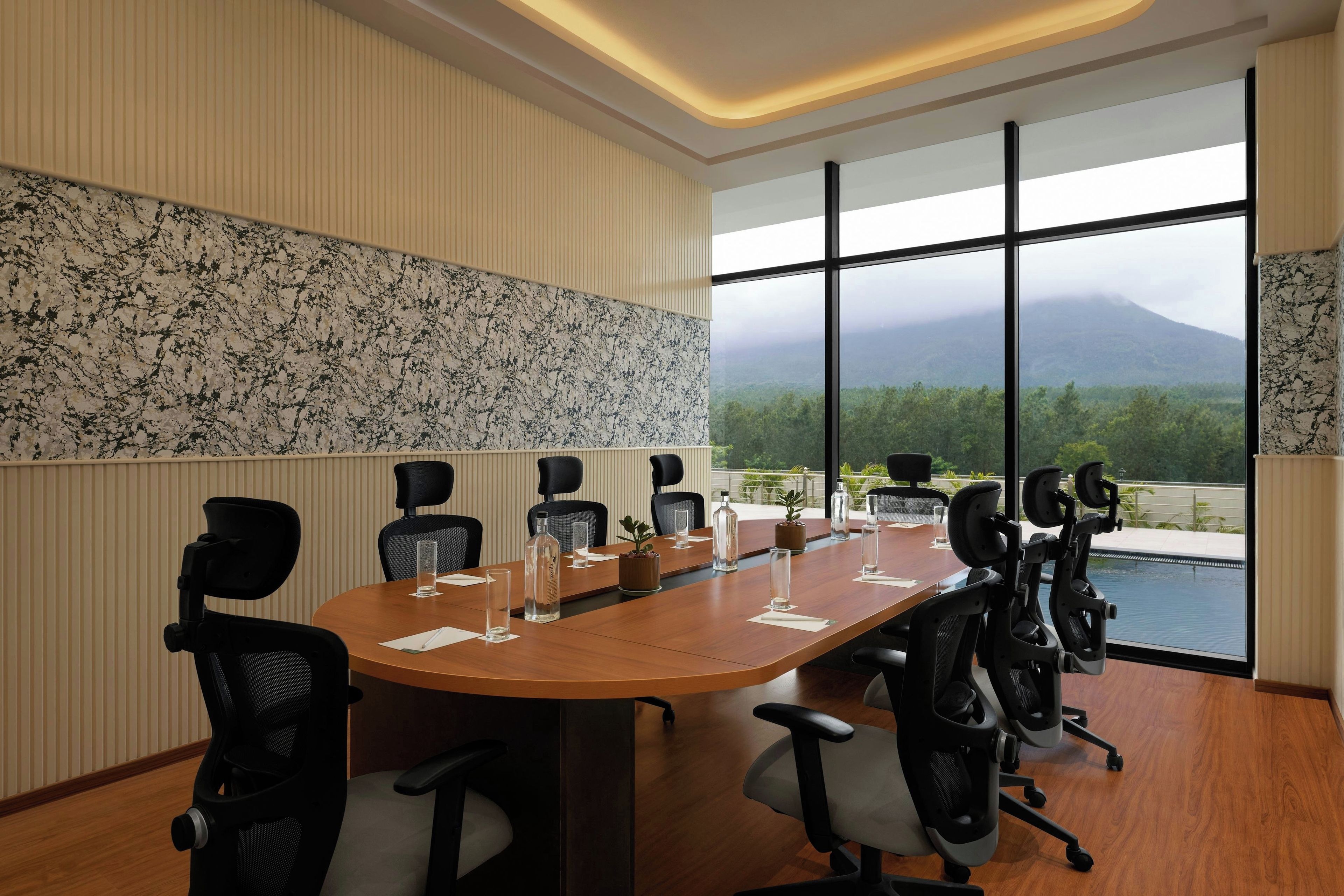 A conference room with a long table, chairs, and a view of a mountainous landscape through large windows.