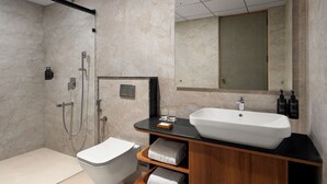 Ett modernt badrum med en stor spegel, ett vitt handfat och en duschhörna.