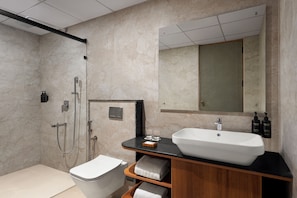 A modern bathroom with a large mirror, a white sink, and a shower area. - Ug The Fern Resort & Spa Chikmagalur, Series By Marriott (Chikkamagaluru)
