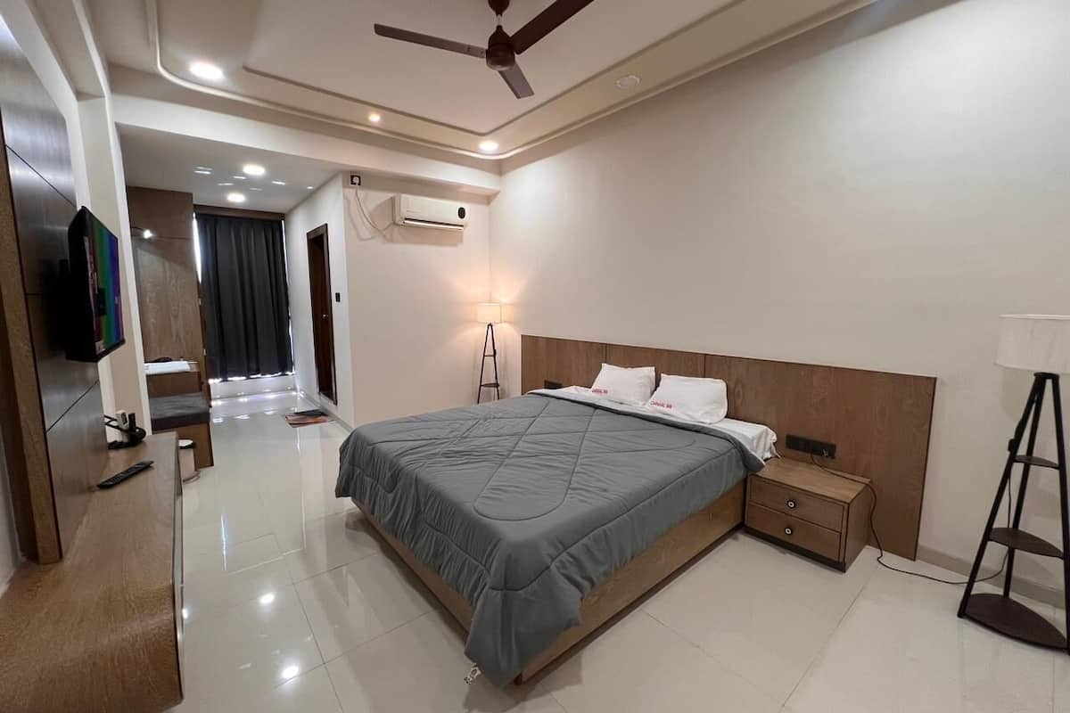 A modern bedroom with a bed, bedside tables, a ceiling fan, and an air conditioning unit.