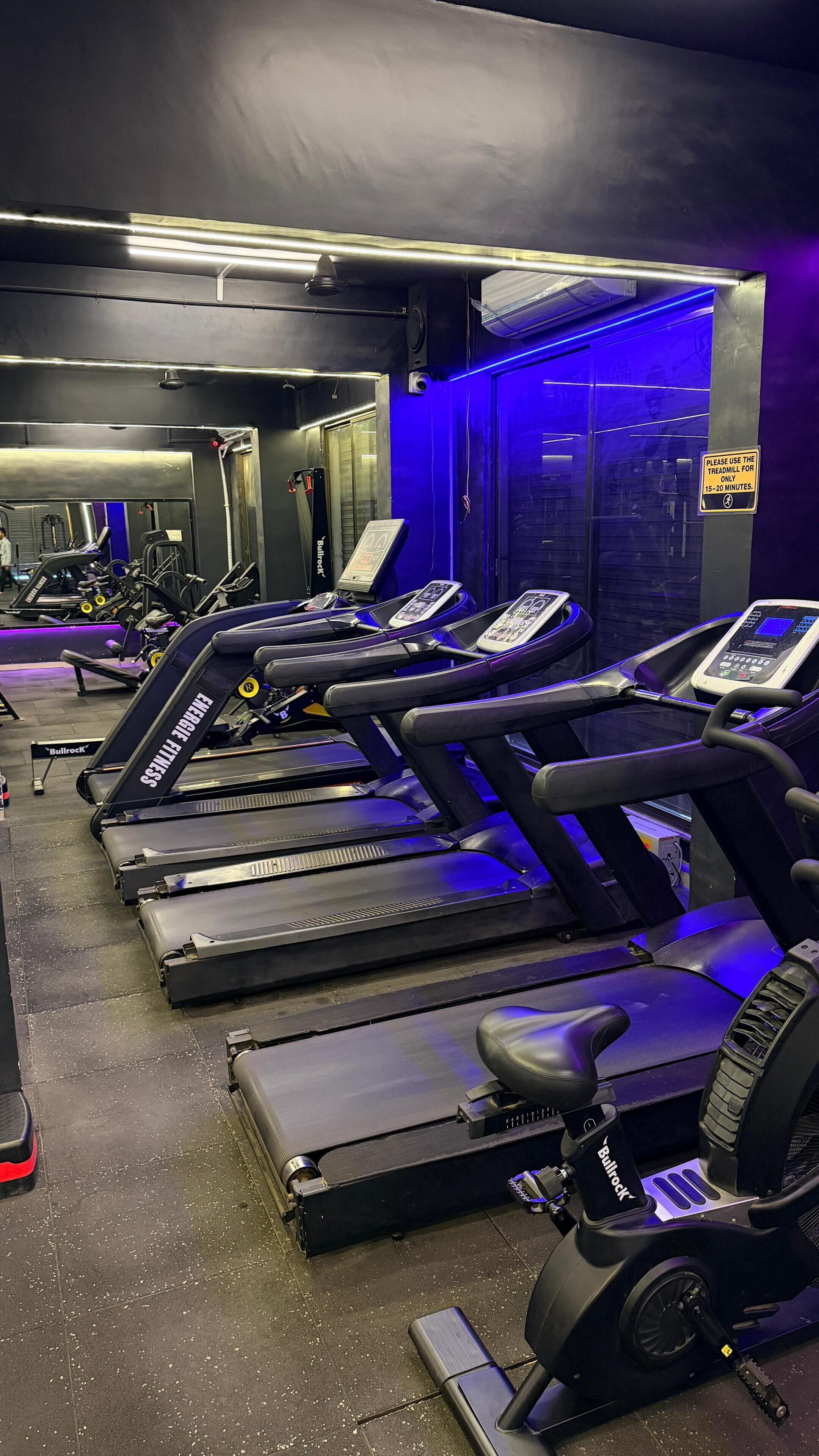 A gym with multiple treadmills, exercise equipment, and a sign indicating treadmill usage time.