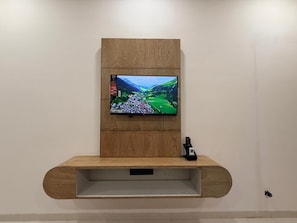 Ein an der Wand befestigter Fernseher mit Fernbedienung auf einem Holzboden.