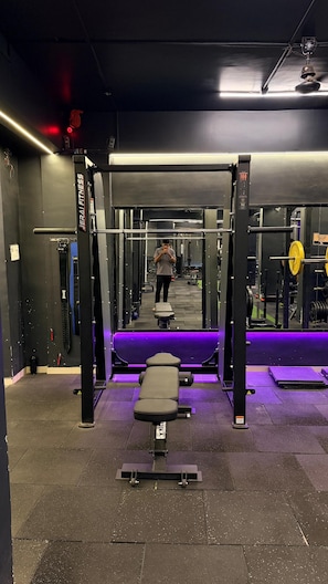 Ein Fitnessraum mit Gewichten, einer Bank und einem Spiegel.