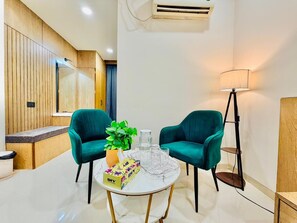 A modern room with teal chairs, a white round table, a potted plant, and a lamp.