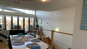 A dining area with a table set for four, chairs, and a view of the outside through large windows. - Villa #91 South Shores ~ The golden hour (Normanville)