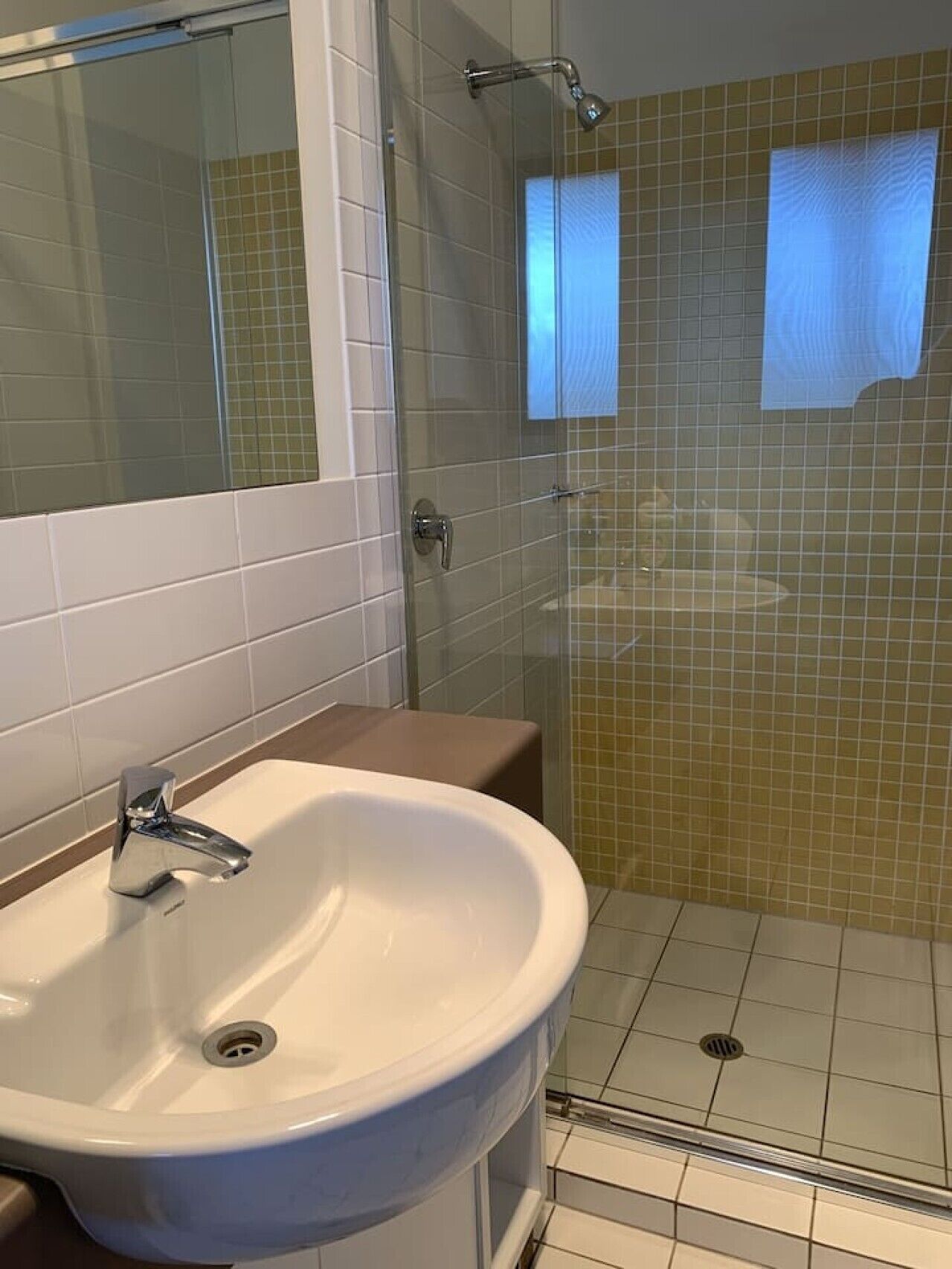 A bathroom with a white sink, a glass shower enclosure, and a mirror.