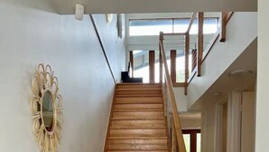 A wooden staircase with a handrail, a mirror on the wall, and a view of the upper floor. - Villa #41 South Shores ~ Dune side escape (Normanville)