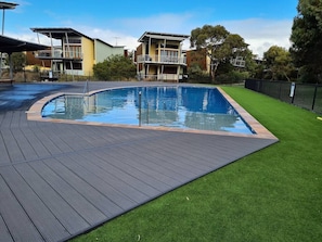 A swimming pool with a wooden deck and artificial grass. - Villa #13 South Shores ~ Water facing escape (Normanville)