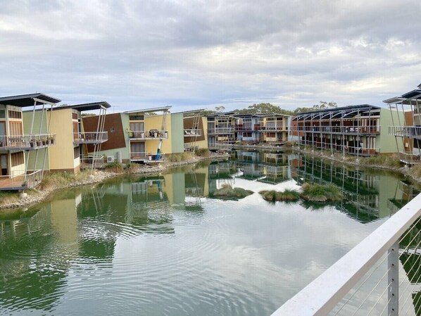 A residential area with multi-story buildings, a calm water body, and a white railing.