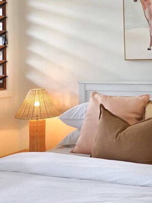 Ein Bett mit weißer Bettwäsche, eine Lampe und ein Gemälde an der Wand.
